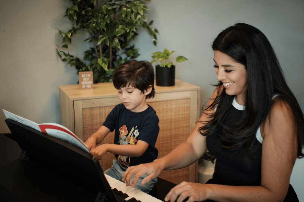 Piano teacher and young student reading a book together at the piano